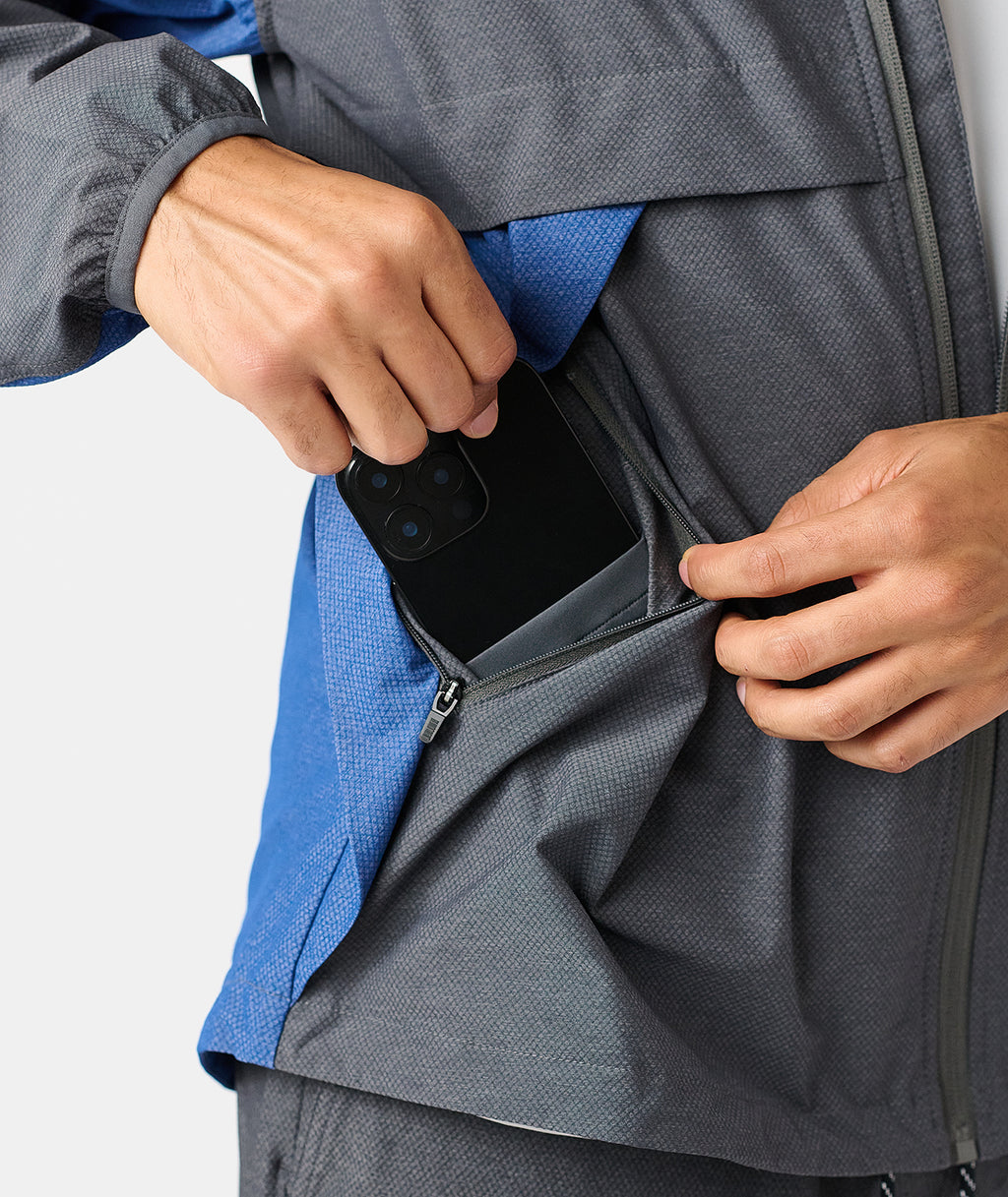 Charcoal full-zip jacket with blue interior lining, worn with hand holding open pocket containing a smartphone. - 6