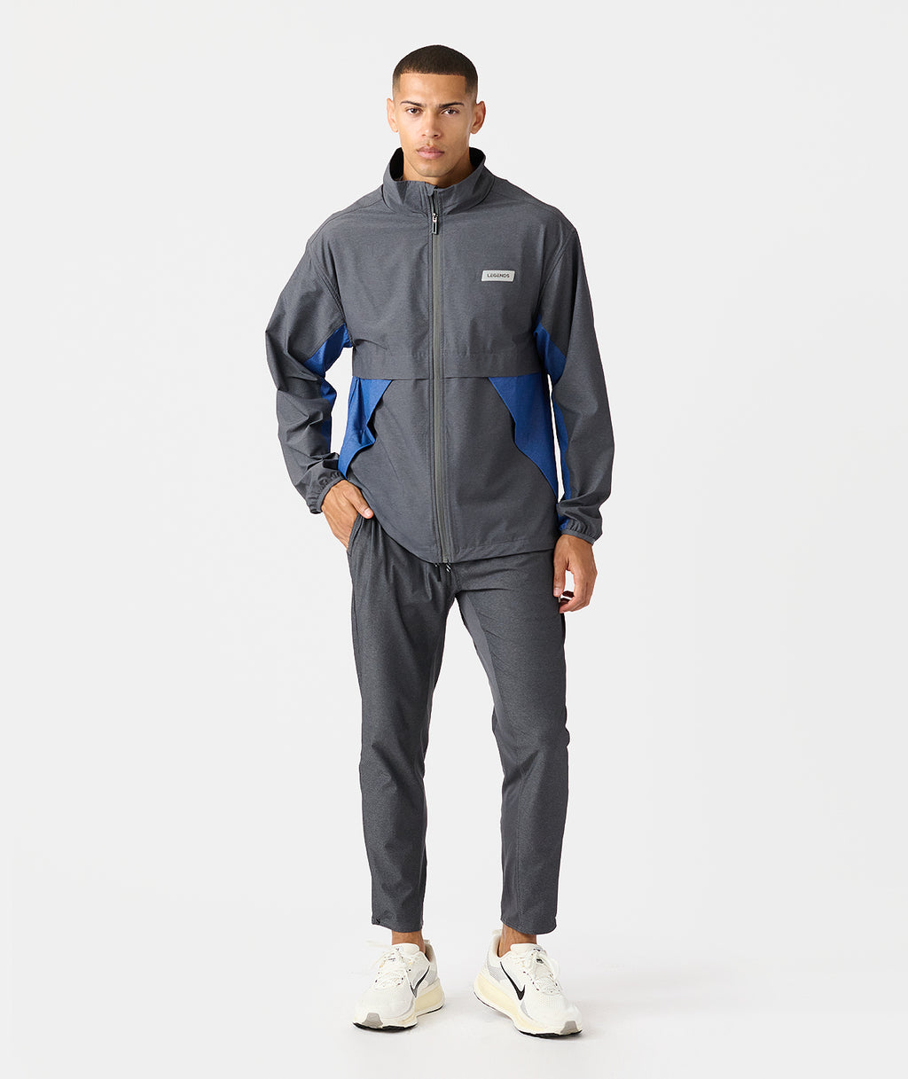Charcoal full-zip jacket with blue side panels and matching joggers, displayed on male model. - 9