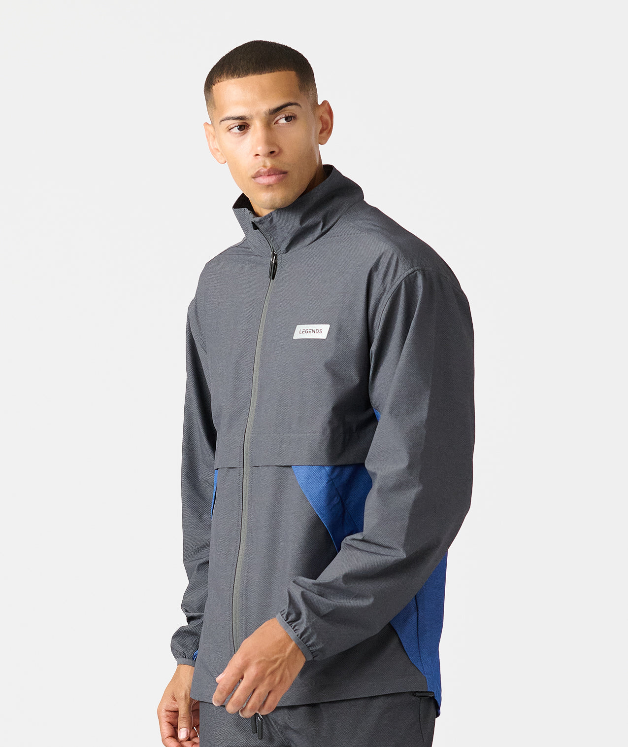 Man wearing charcoal and blue full-zip hooded jacket with white brand label on chest. - 3