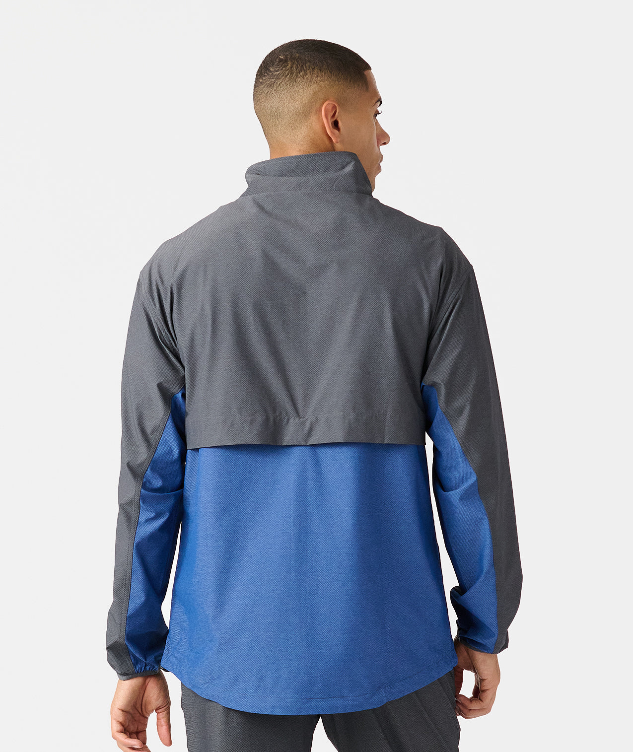 Man wearing charcoal and blue colorblock full-zip jacket with high collar, shown from back. - 2