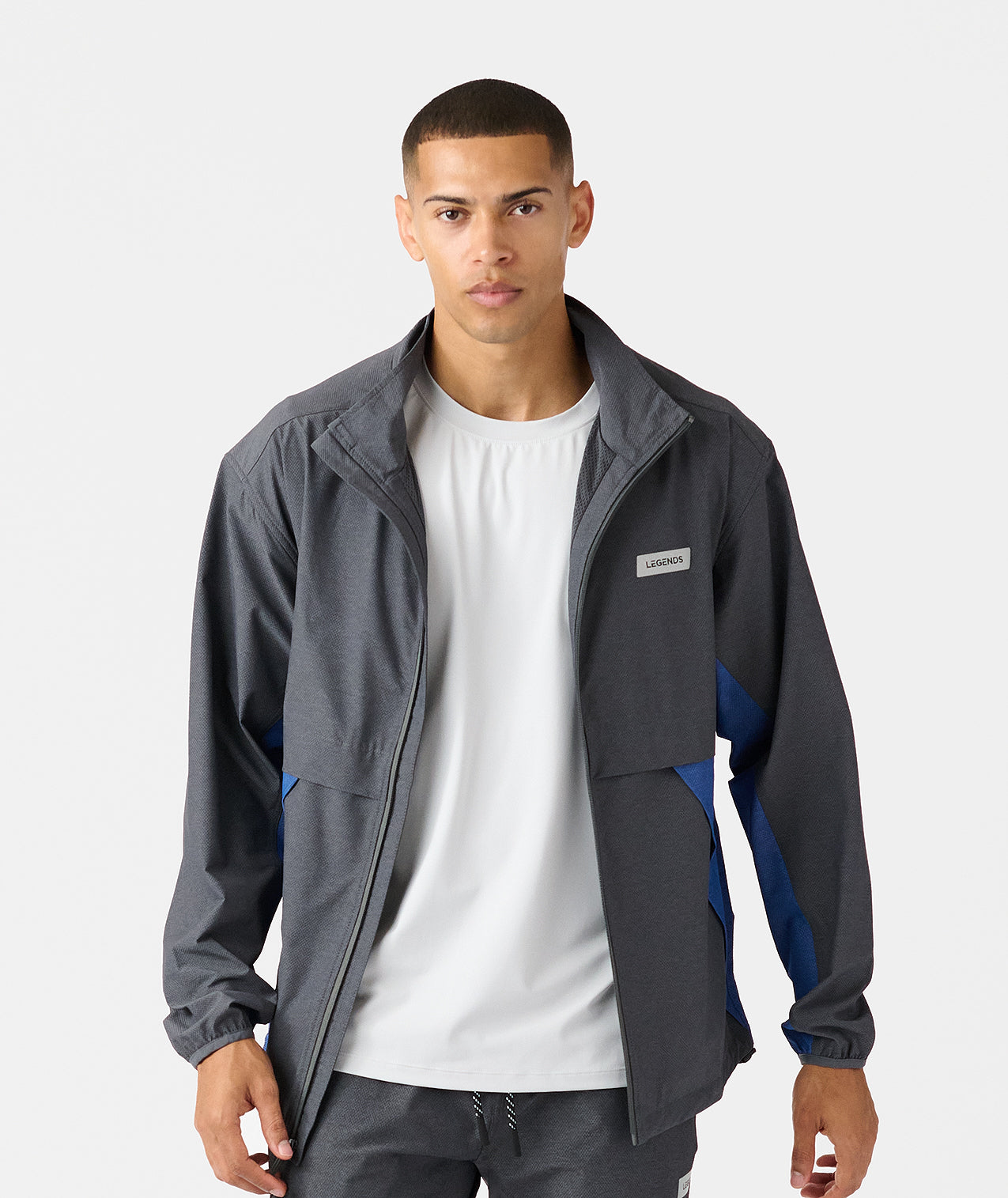 Charcoal full-zip jacket with blue side panels and branded chest patch worn over white t-shirt. - 4
