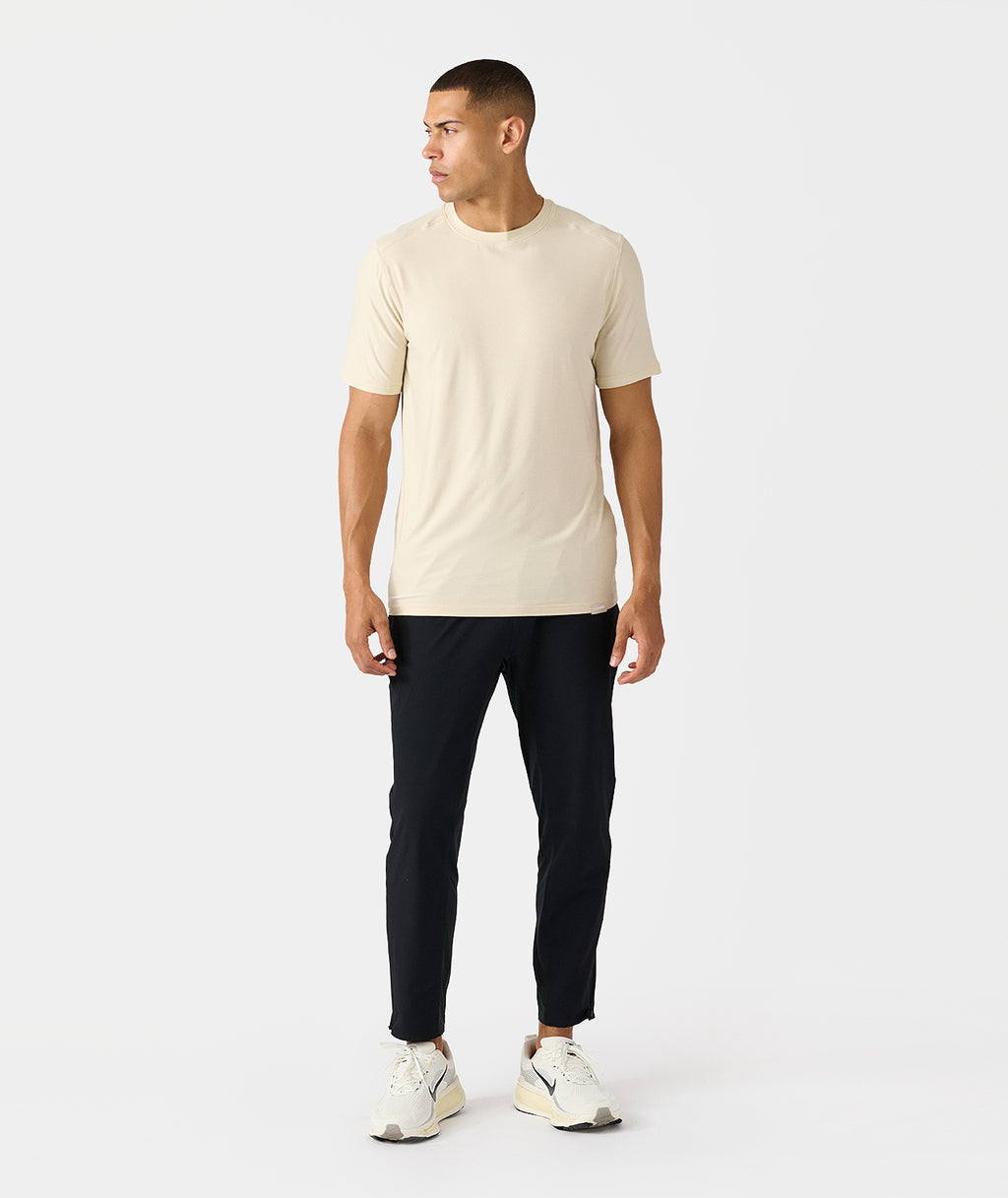 Man wearing black tapered pants with cream t-shirt and white sneakers. - 9