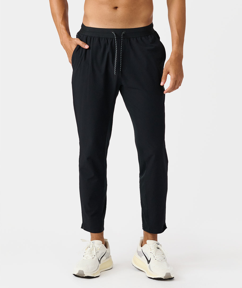 Black drawstring pants with elastic waistband and side pockets, shown on male model wearing white sneakers. - 1