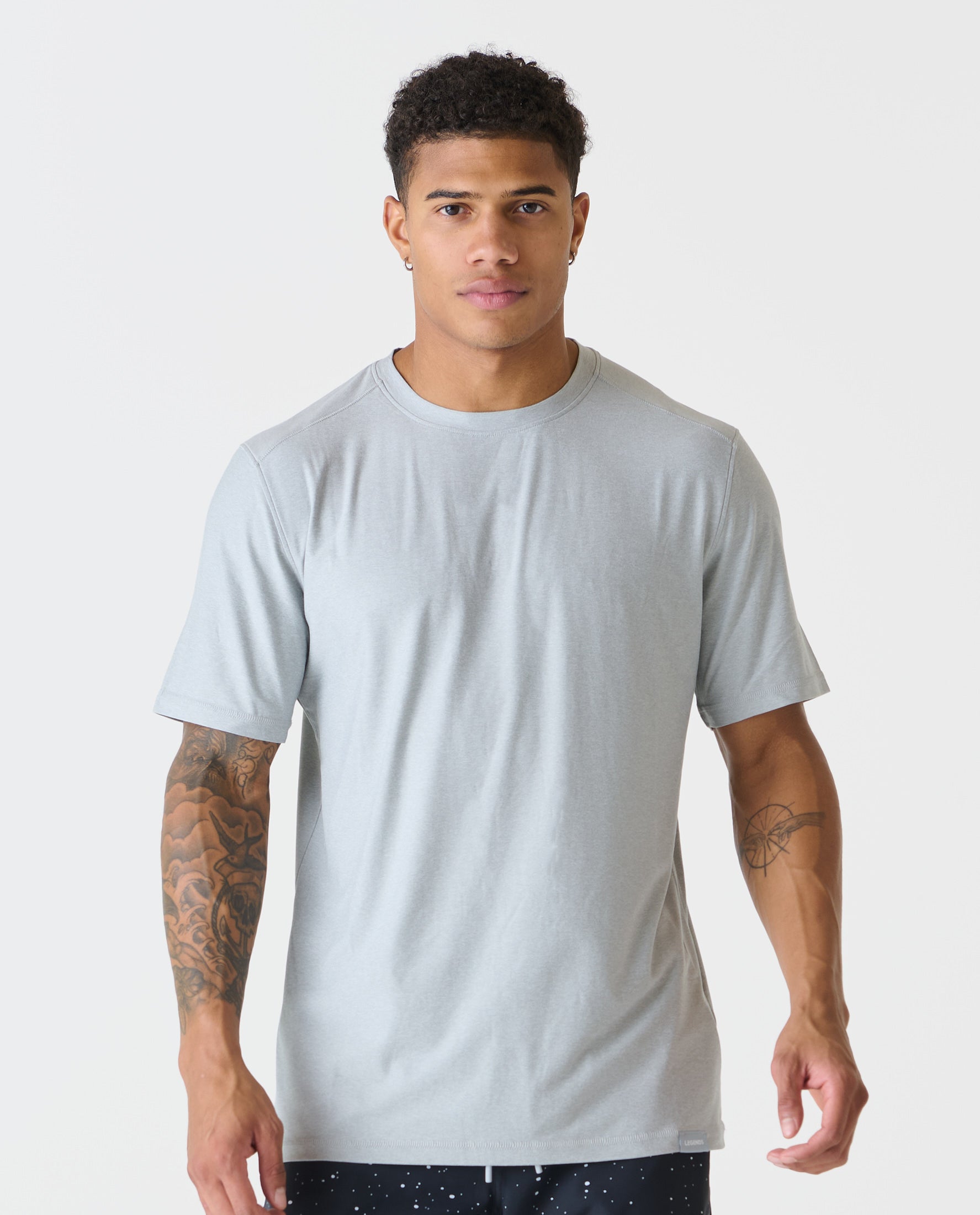 Heather gray short-sleeve crew neck tee on male model with dark hair and visible arm tattoos.