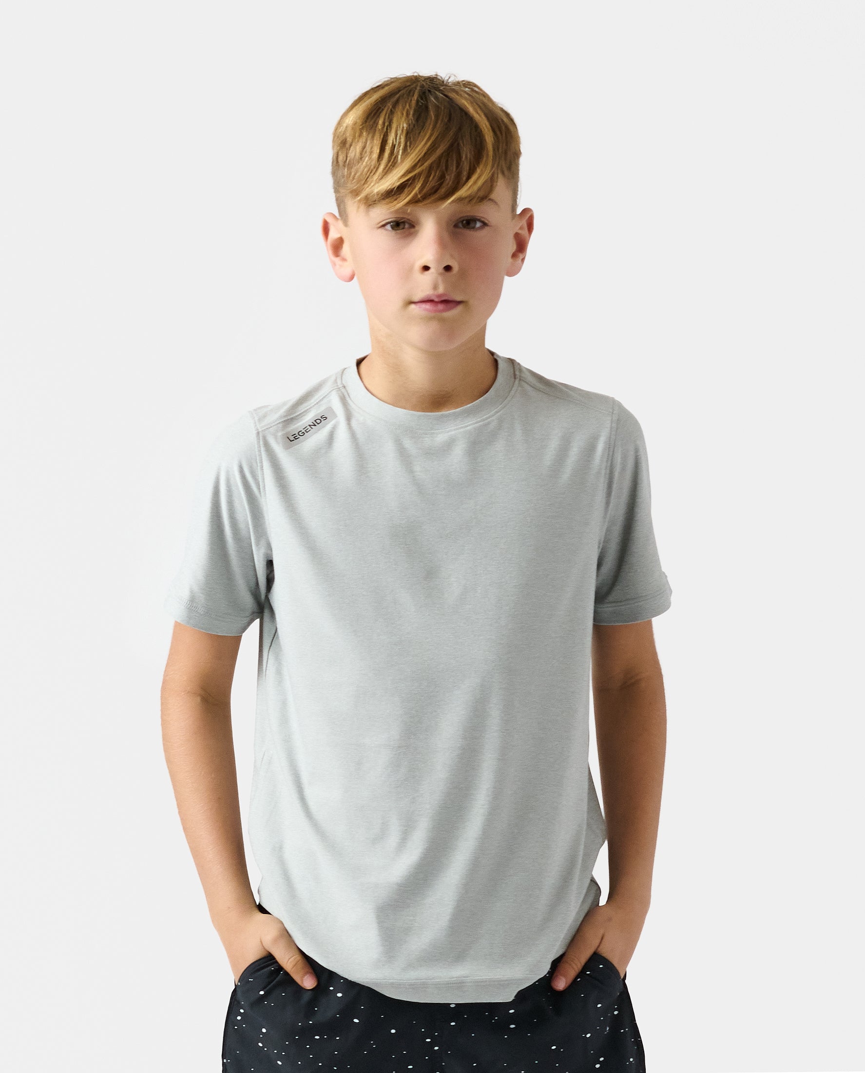 Child wearing heather gray short-sleeve crew neck t-shirt with small logo on shoulder.
